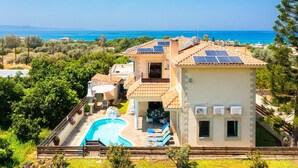 Una villa con piscina, paneles solares y vistas al mar.