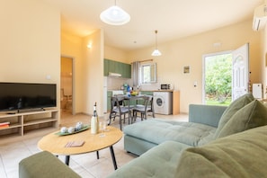 Relax in a comfortable seating area with a sofa and dining table for two, featuring a flat-screen TV and convenient laundry facilities.