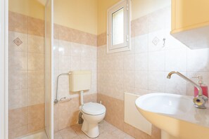 Ein kleines Badezimmer mit Toilette, Dusche und Waschbecken.