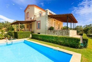 A two-story house with a swimming pool, stone exterior, and a covered patio.
