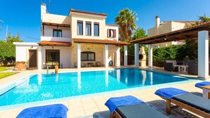 Une maison à deux étages avec une piscine, un espace salon extérieur et une pergola.