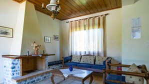 A living room with a brick fireplace, a blue sofa, a wooden coffee table, and a window with curtains. - Ekklisies Tria Large Private Pool A C Wifi - 2090 (Apokoronas)