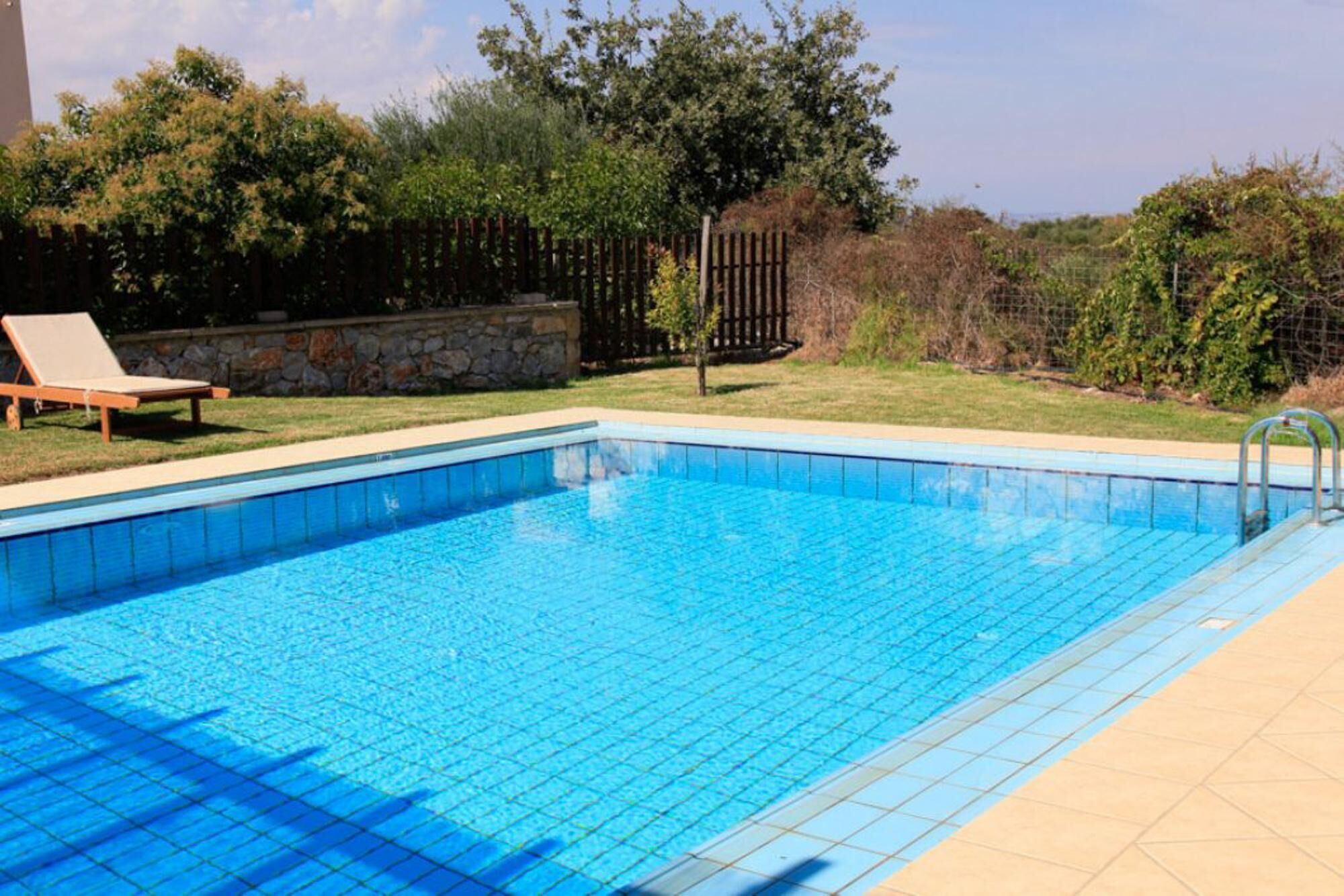 A rectangular swimming pool with clear blue water, surrounded by a tiled deck.