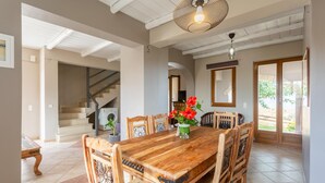 Un coin repas avec une table et des chaises en bois, un vase rempli de fleurs rouges et un luminaire suspendu.