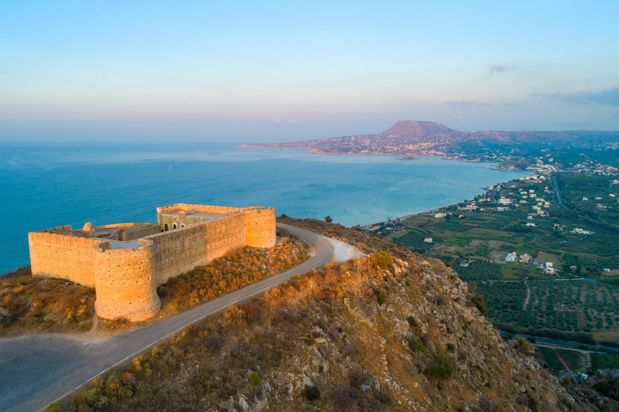 Eine historische Steinbefestigung mit Blick auf eine Küstenstadt und das Meer.