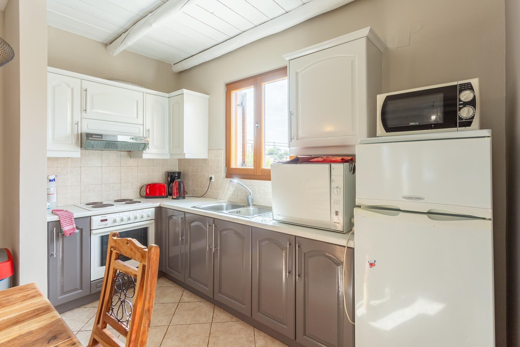 A kitchen with white cabinets, a stove, a microwave, and a refrigerator.