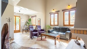 A spacious living room with a high ceiling, a dining area with a table and chairs, and a large window with a view. - Villa Stratos Large Private Pool Sea Views A C Wifi Eco-friendly - 2117 (Chania)