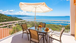 A balcony with a table, chairs, and a large umbrella overlooking a scenic view of the sea and hills. - Villa Amalia Large Private Pool Walk to Beach Sea Views A C Wifi - 2120 (Corfu)