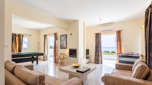 A spacious living room with a pool table, comfortable seating, a fireplace, and a view of the sea. - Kalisto Beach Villa Large Private Pool Walk to Beach Sea Views A C Wifi Car Not Required - 2137 (Ayia Marina Chrysochous)