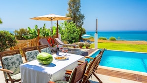 A poolside dining area with a table, chairs, and a watermelon centerpiece. - Kalisto Beach Villa Large Private Pool Walk to Beach Sea Views A C Wifi Car Not Required - 2137 (Ayia Marina Chrysochous)