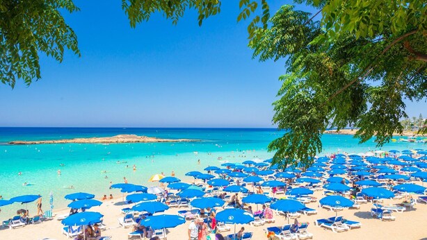 A beach with numerous blue umbrellas and sun loungers, a clear blue sky, and the sea in the background. - Villa Iliada Large Private Pool Walk to Beach A C Wifi Car Not Required - 2143 (Polis)