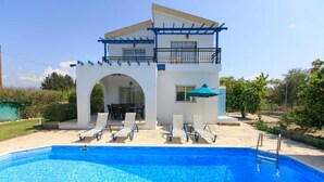Un edificio de dos pisos con piscina, mobiliario exterior y un patio cubierto.