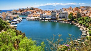 Una località costiera con un porto turistico, edifici con balconi e una vista limpida sul mare e sulle montagne sullo sfondo.