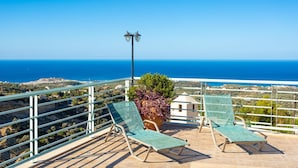 A balcony with two green lounge chairs, a potted plant, and a street lamp overlooking a coastal view. - Villa Selini Private Pool Sea Views A C Wifi Eco-friendly - 2158 (Rethymno)