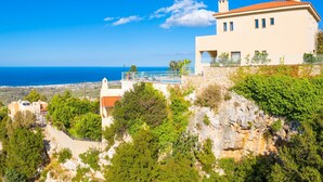 A coastal house with a stone retaining wall, a balcony with a railing, and a view of the sea. - Villa Selini Private Pool Sea Views A C Wifi Eco-friendly - 2158 (Rethymno)