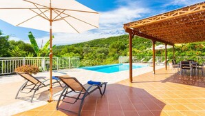 A poolside area with lounge chairs, a pergola, and a view of a lush green landscape. - Villa Peach Large Private Pool Walk to Beach Sea Views A C Wifi Car Not Required - 2181 (Kefalonia)