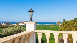 A balcony with a stone balustrade overlooking a coastal landscape with houses and greenery. - Villa Clementina Large Private Pool Walk to Beach Sea Views A C Wifi Eco-friendly - 2183 (Ayia Marina Chrysochous)
