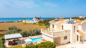 A coastal residential area with houses, a swimming pool, and a view of the sea. - Villa Rose Large Private Pool Walk to Beach Sea Views A C Wifi - 2184 (Ayia Marina Chrysochous)