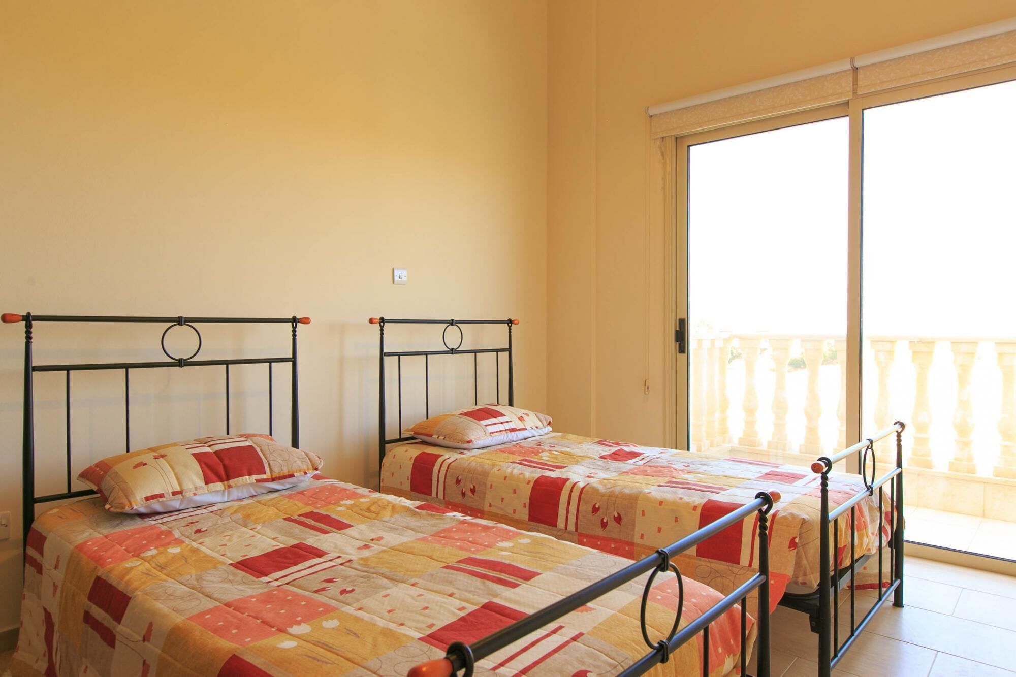 A room with two beds, a balcony with a view, and a window.
