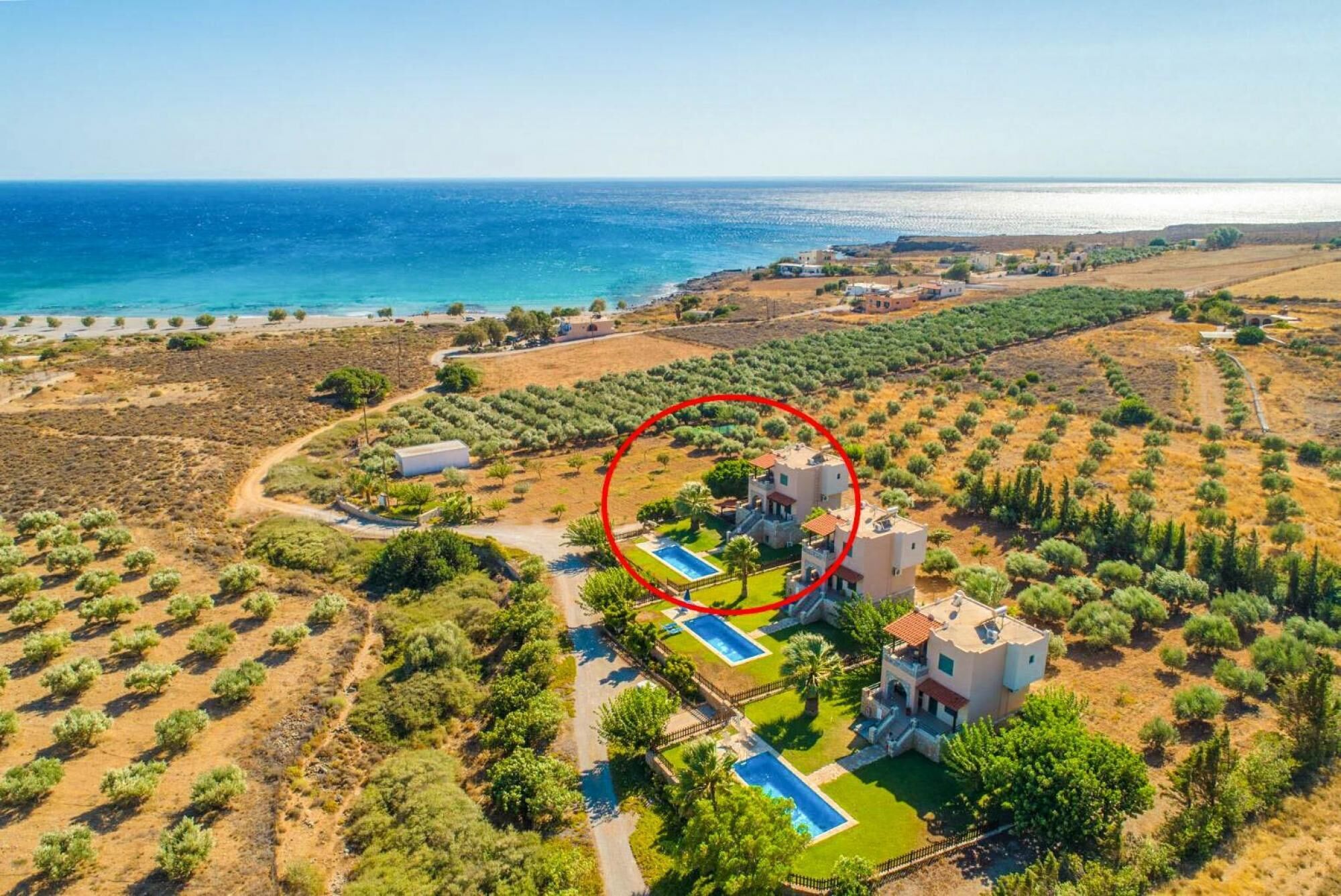 Vista aérea de una propiedad costera con piscina, varias edificaciones y vistas al mar.