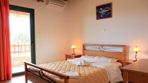 A bedroom with a wooden bed, two bedside tables with lamps, a window with curtains, and a painting on the wall. - Theo Beach Villa Large Private Pool Walk to Beach Sea Views A C Wifi Car Not Required - 1843 (Sfakia)