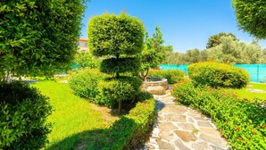 Ein gepflegter Garten mit verschiedenen Sträuchern und einer kleinen Steinstruktur, durch den ein Kiesweg führt.