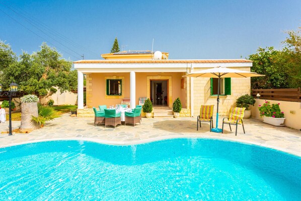 A house with a swimming pool, outdoor furniture, and a covered patio area.
