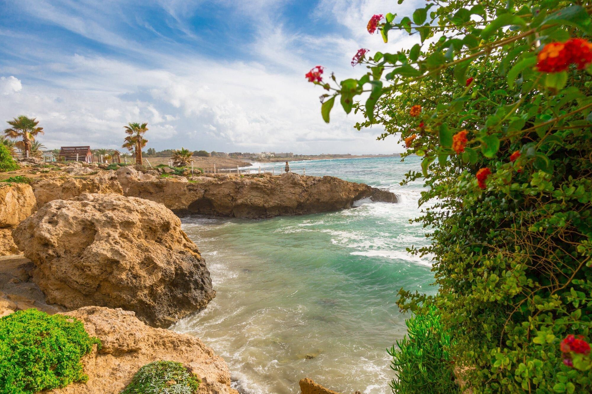 A coastal landscape with rocky cliffs, clear turquoise waters, and lush greenery.