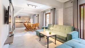 A modern living room with a green sofa, a coffee table, and a dining area with wooden chairs and a table. - Villa Emel Paradise Private Pool A C Wifi Car Not Required Eco-friendly - 2232 (Ortaca)