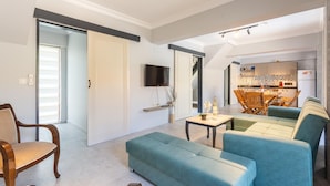 A modern living room with a sofa, a wooden chair, and a dining area with a table and chairs. - Villa Emel Paradise Private Pool A C Wifi Car Not Required Eco-friendly - 2232 (Ortaca)
