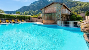 A swimming pool with lounge chairs, a bar area, and a mountain backdrop. - Villa Emel Paradise Private Pool A C Wifi Car Not Required Eco-friendly - 2232 (Ortaca)