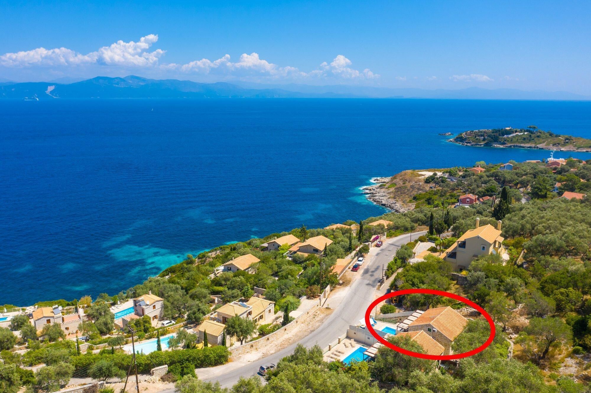 A coastal village with houses, a road, and a view of the sea.