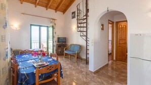 A dining area with a table set for two, a television, and a spiral staircase. - Villa Anastasia Large Private Pool Walk to Beach Sea Views A C Wifi Car Not Required - 2248 (Paxos)