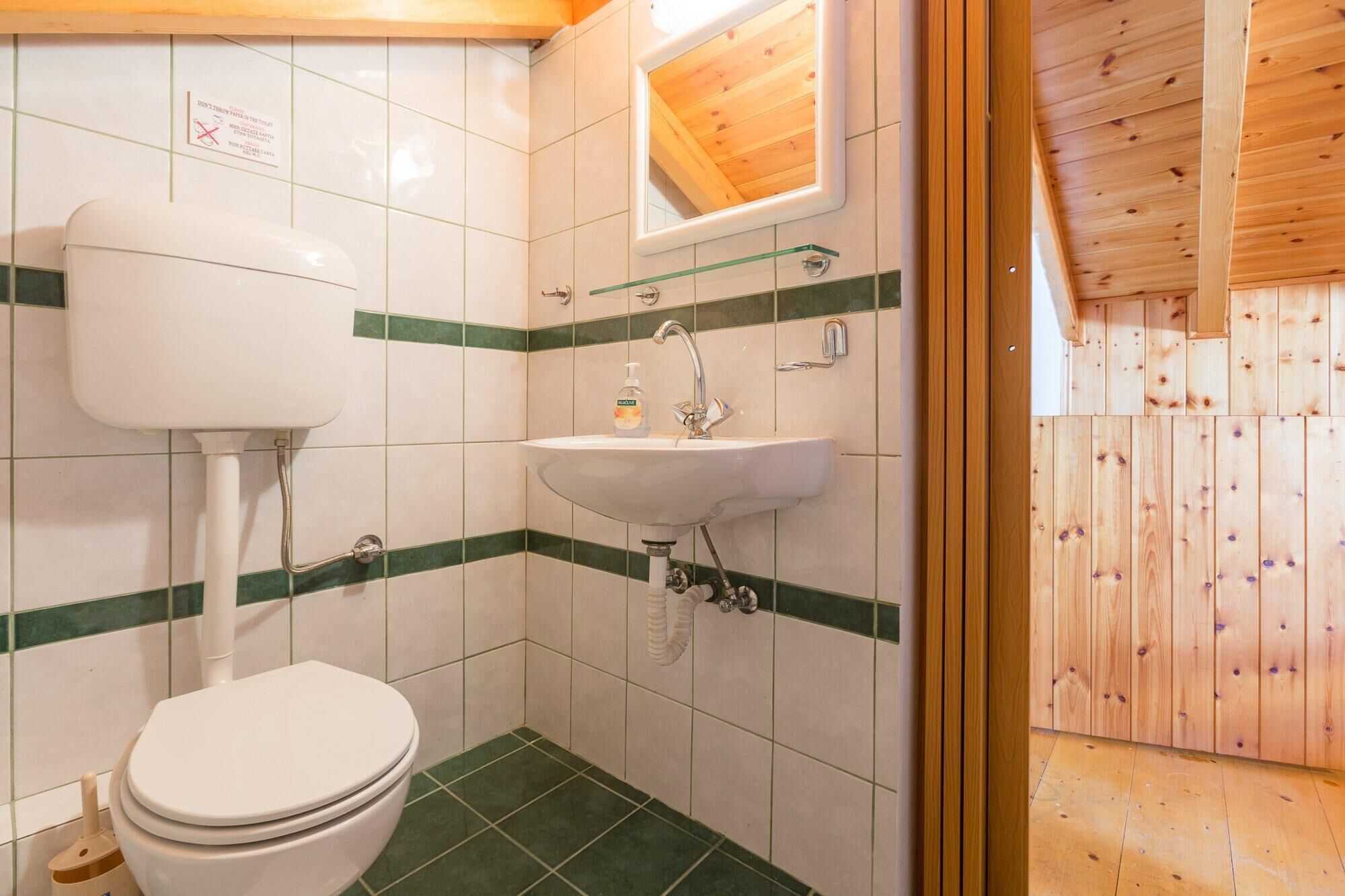 A small bathroom with a toilet, sink, and mirror.