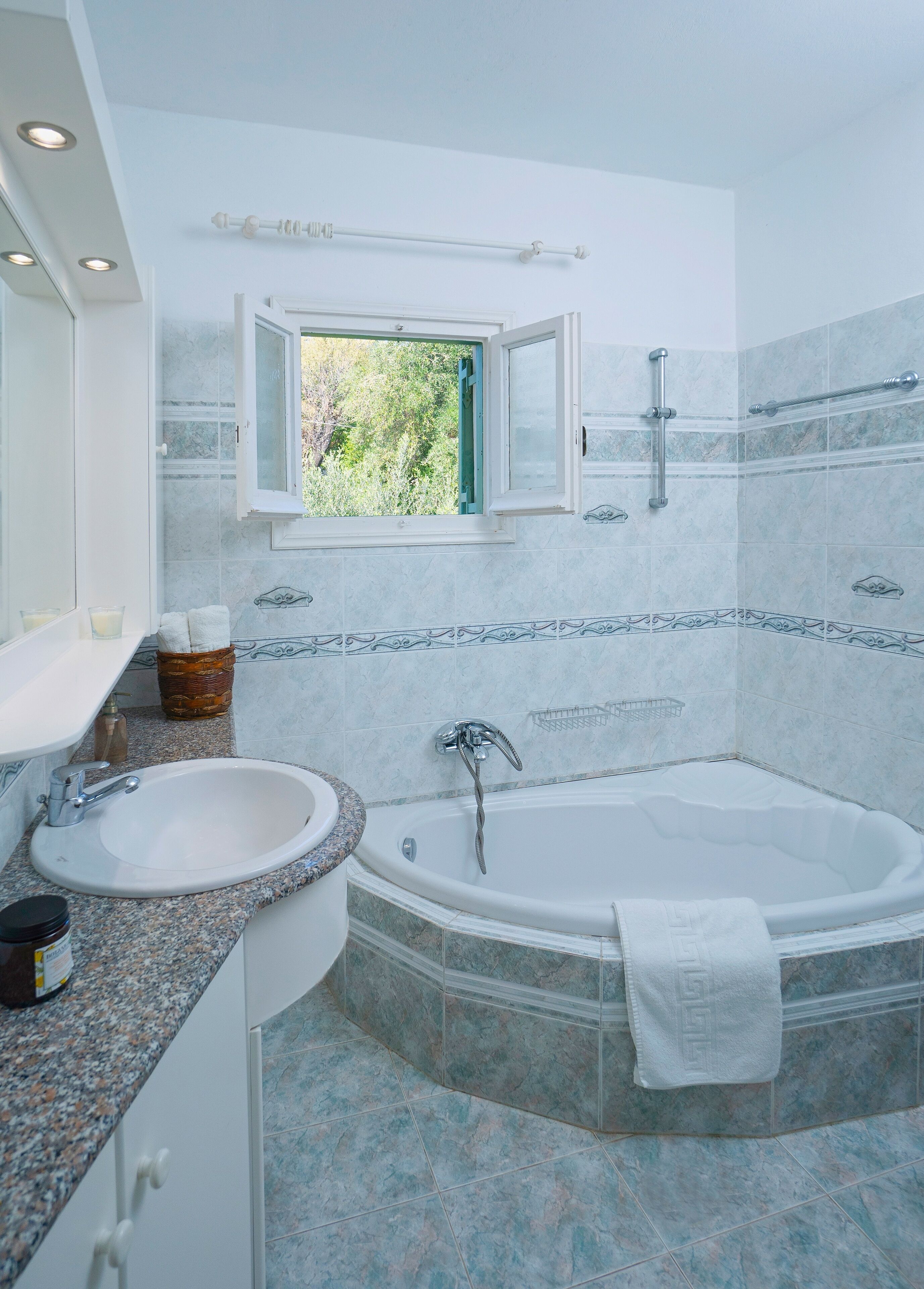 A bathroom with a sink, bathtub, and window.