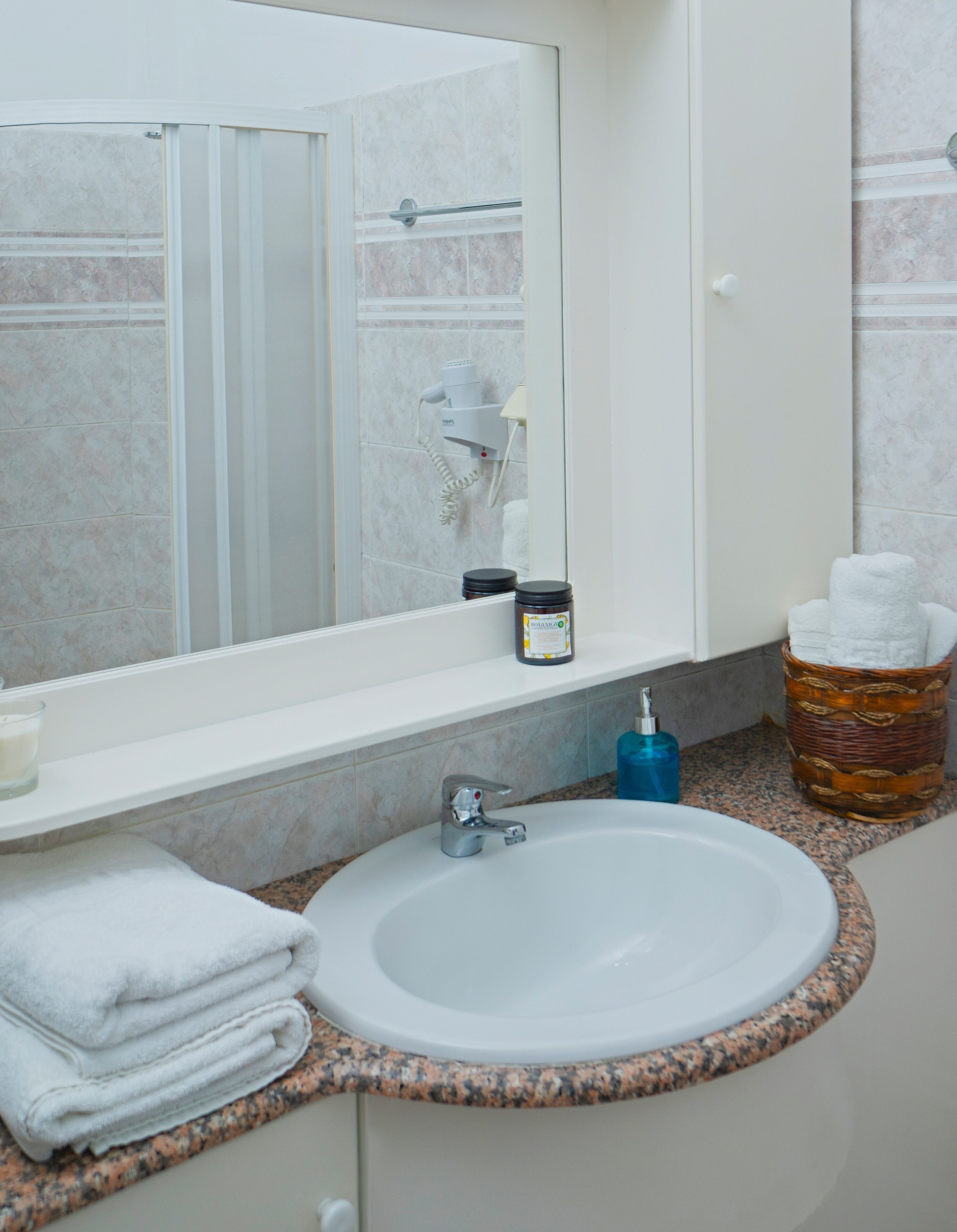A bathroom with a sink, mirror, and toiletries.