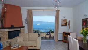 Una sala de estar con chimenea, un sofá, una mesa de comedor y vistas al mar.