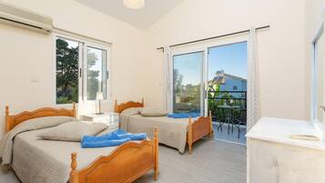 A bedroom with two wooden beds, a balcony with a table and chairs, and a large window.