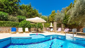 A swimming pool with lounge chairs and umbrellas, surrounded by stone walls and trees. - Villa Pelagos Large Private Pool Sea Views A C Wifi Eco-friendly - 2310 (Rethymno)