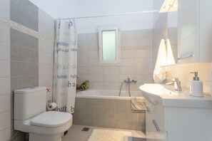 A bathroom with a toilet, bathtub, and sink.