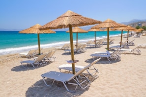 A beach with sun loungers and thatched umbrellas. - Villa Asimenia Large Private Pool Sea Views A C Wifi Eco-friendly - 2388 (Rethymno)