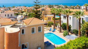 Un quartier résidentiel doté d’une piscine, de palmiers et offrant une vue sur la mer.