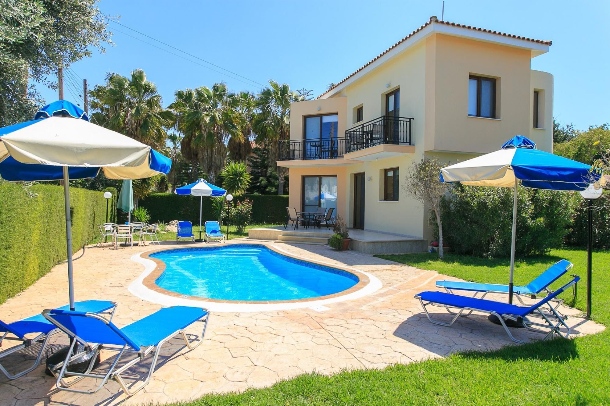 A two-story house with a swimming pool, outdoor seating, and a well-maintained garden.