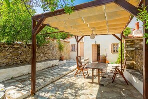 Un espace extérieur abrité, doté de murs en pierre et d’une pergola.