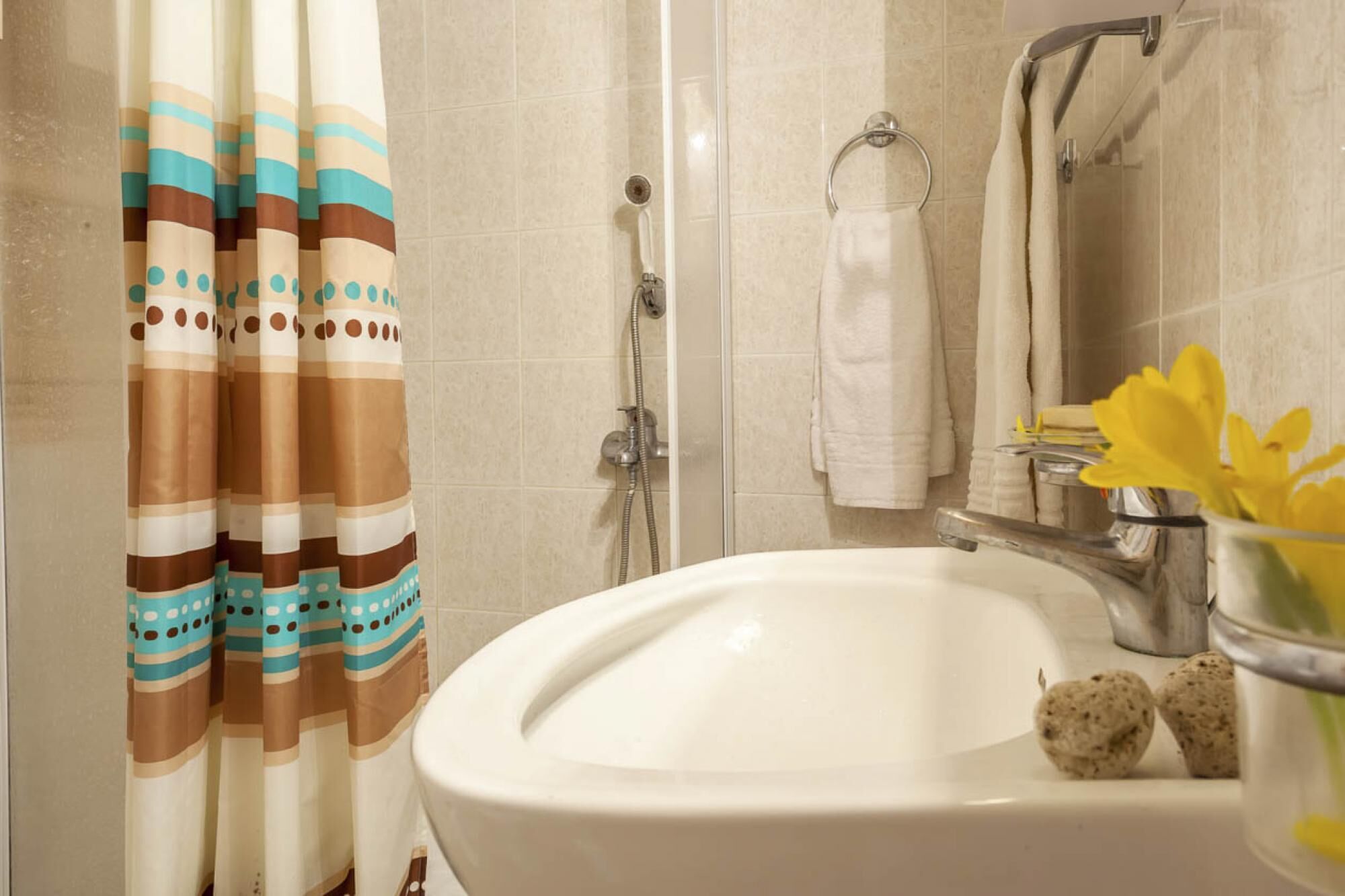 A bathroom with a shower, a sink, and a towel rack.