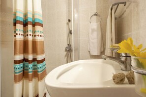 Une salle de bain avec une douche, un lavabo et un porte-serviettes.