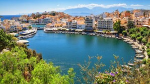 Un pueblo costero con un puerto deportivo, edificios y montañas al fondo.