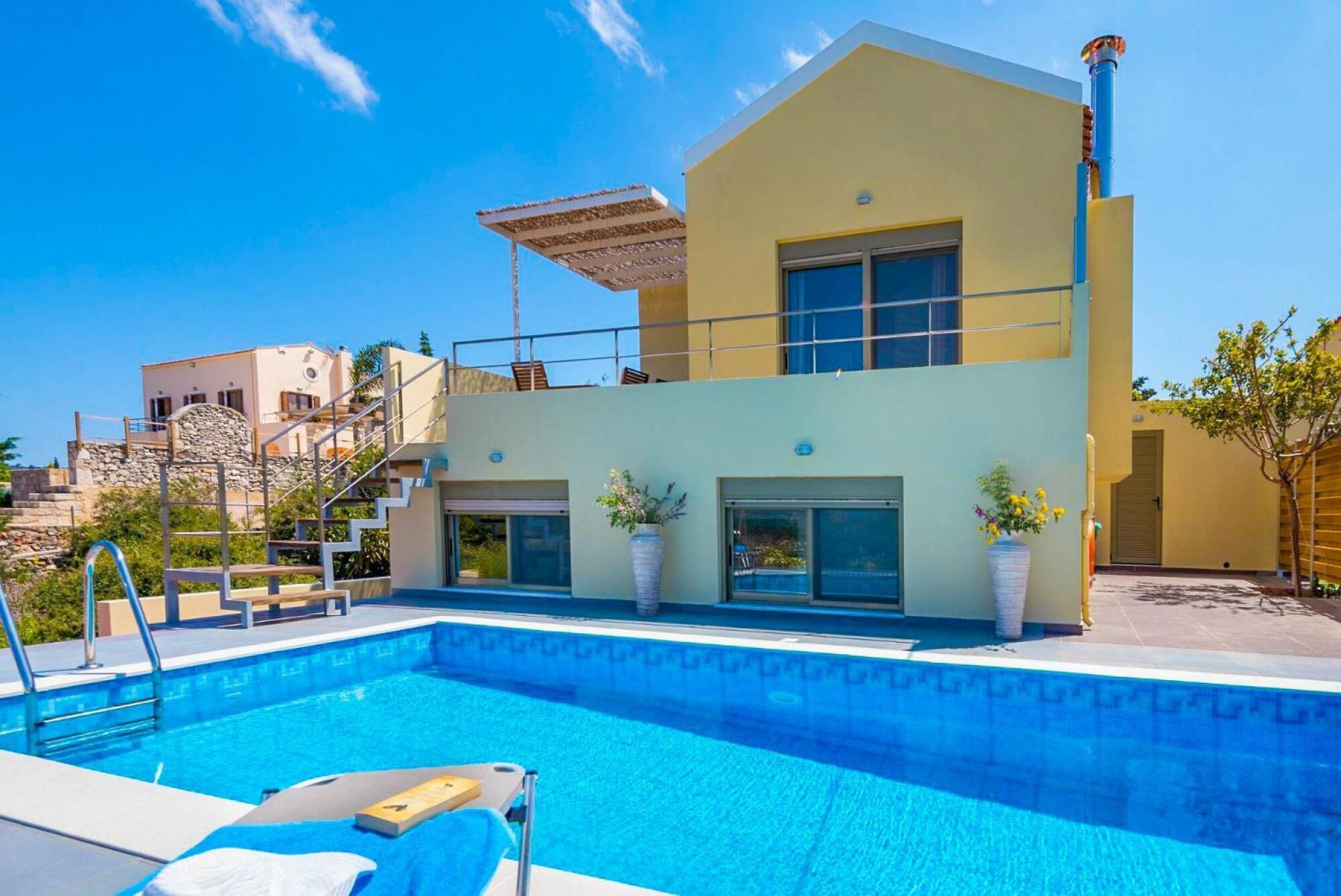 A modern two-story house with a swimming pool in the foreground.