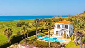 A white villa with a pool, surrounded by lush greenery and palm trees, overlooking a clear blue sea. - Villa Pelagos Large Private Pool Walk to Beach Sea Views A C Wifi - 2429 (Pomos)