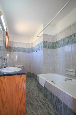 A modern bathroom with a wooden vanity, a bathtub, and a shower area.